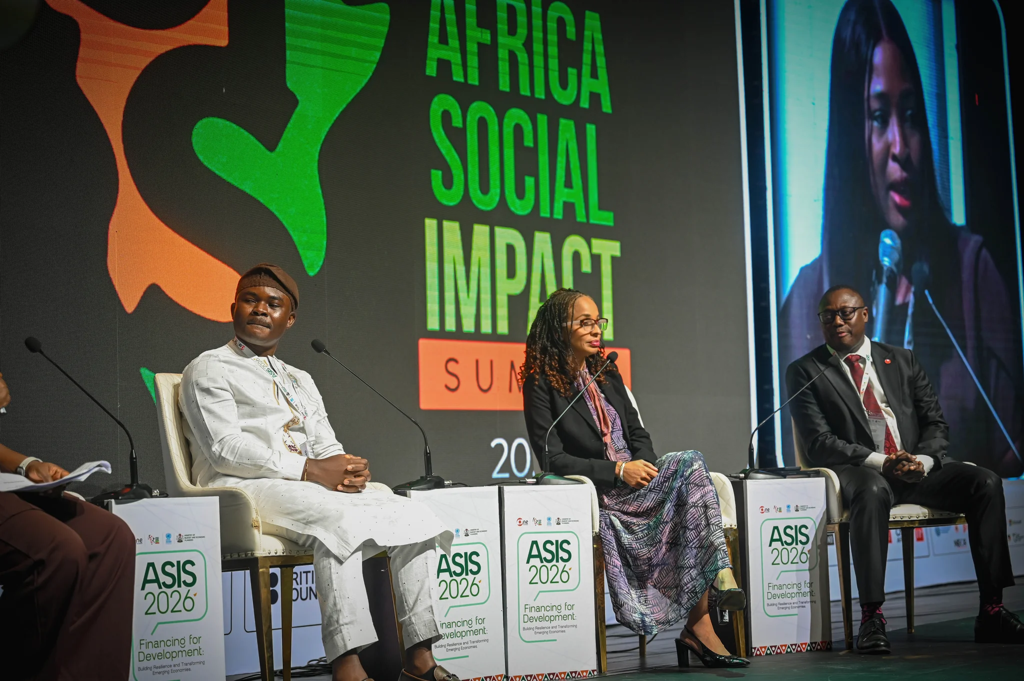 High-resolution stage shot of Dr. Alabi seated on an official panel chair alongside international co-panelists at the Africa Social Impact Summit (ASIS 2026) under the "Financing for Development" backdrop.