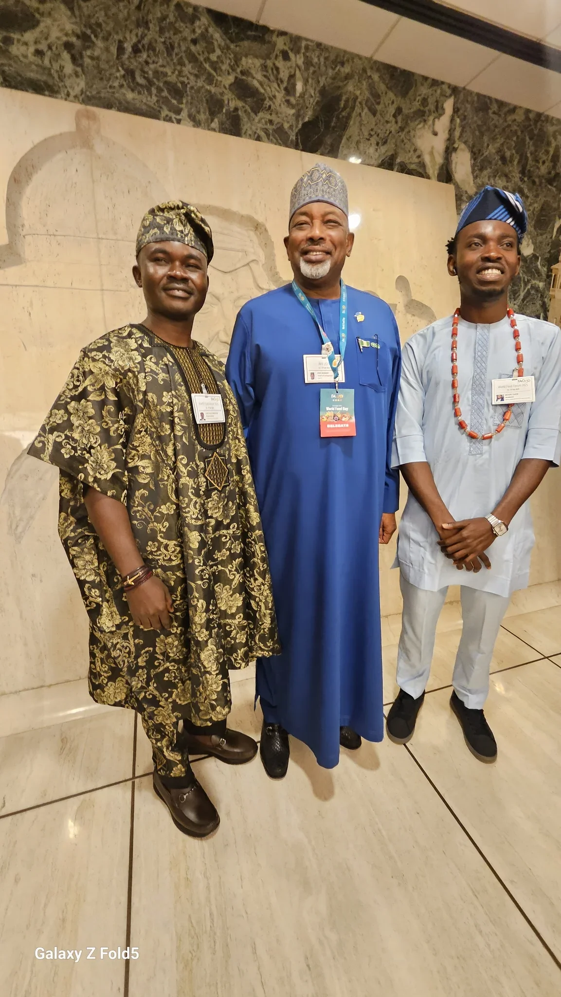 Dr. Segun Alabi in gold traditional Agbada standing alongside Minister Abubakar Kyari and a fellow Nigerian delegate at the UN FAO Headquarters in Rome.