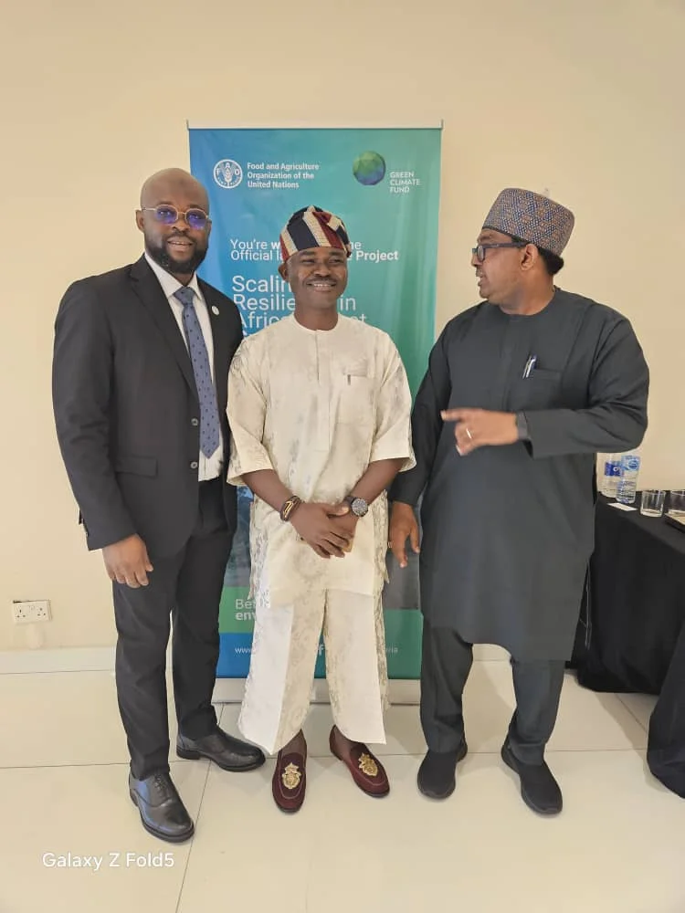 Dr. Alabi in a white Agbada standing in front of an official UN FAO and Green Climate Fund backdrop alongside international delegates.