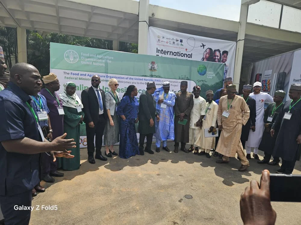 Wide outdoor photo of Dr. Alabi standing among a large delegation of UN FAO officials and Ministry representatives at an official launch event.